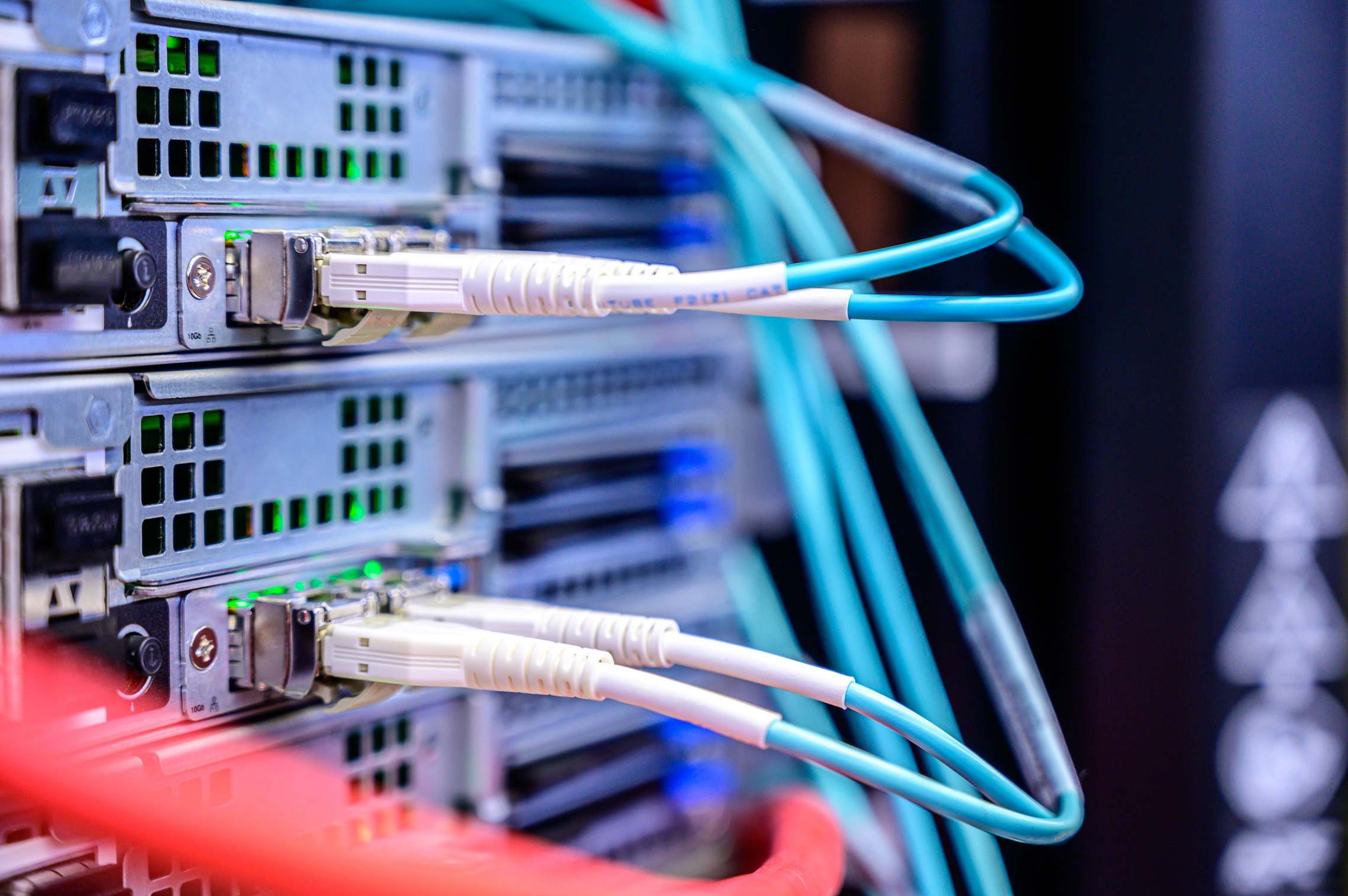 Rows of server racks in a data hall with network cabling